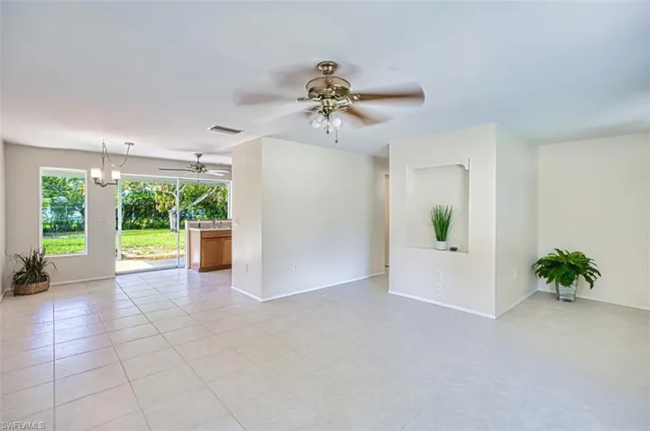 Unfurnished room featuring ceiling fan, light tile patterned flooring, and a chandelier