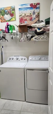 Clothes washing area featuring washer and clothes dryer and light tile patterned floors