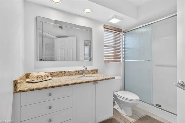 The primary bathroom has newer cabinetry, granite countertop and a large mirror. The shower surround and doors were replaced in Oct 2023.