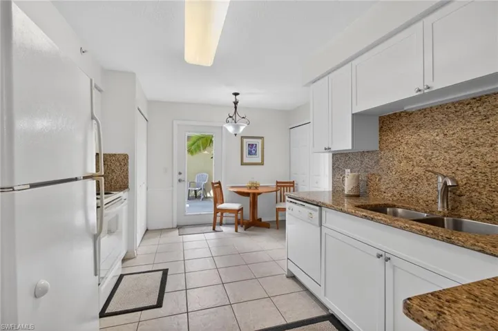 The kitchen features white cabinetry, granite countertops, and tile flooring
