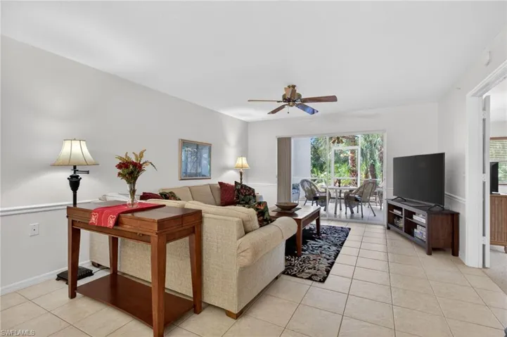 Living area features tiled flooring, a ceiling fan, and sliding glass doors leading to the lanai.