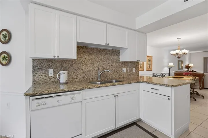 The kitchen features newer white shaker cabinetry, and granite countertops and backsplash.