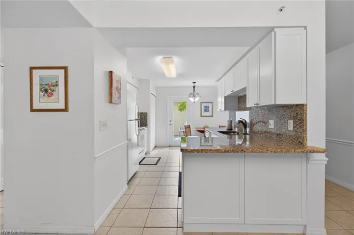 The kitchen features newer white shaker cabinetry, granite countertops and backsplash, and tile floor