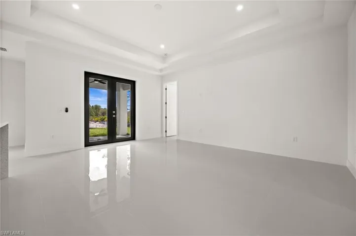 Empty room with french doors, light tile patterned floors, a tray ceiling, and recessed lighting