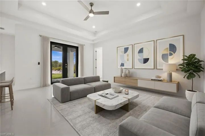 Living area with a ceiling fan, french doors, recessed lighting, and a tray ceiling