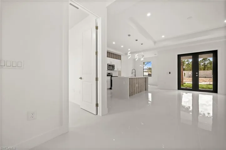 Unfurnished living room with recessed lighting, french doors, and a raised ceiling
