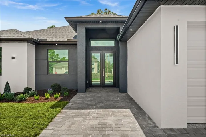 Entrance to property with stucco siding, a shingled roof, and french doors