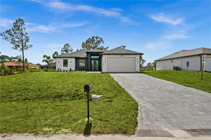 Prairie-style home featuring decorative driveway, an attached garage, a front yard, and stucco siding