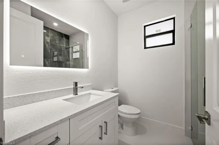 Full bathroom with vanity, a marble finish shower, and a textured wall