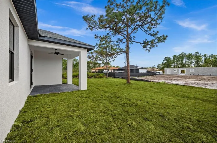 View of green lawn with ceiling fan and a patio area