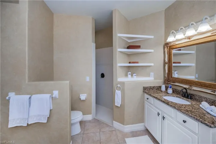 Bathroom featuring tile patterned flooring, vanity, and walk in shower
