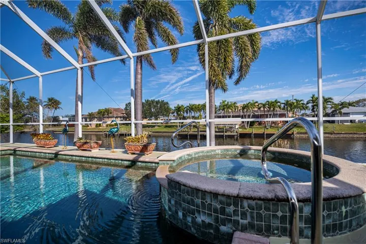 View of pool featuring a water view, a lanai, a pool with connected hot tub, and a boat dock