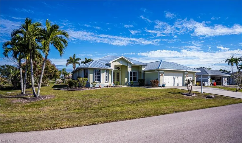 Single story home featuring concrete driveway, an attached garage, a front lawn, and a metal roof