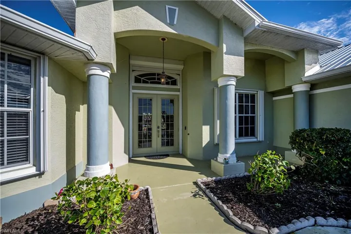 View of exterior entry with stucco siding and french doors