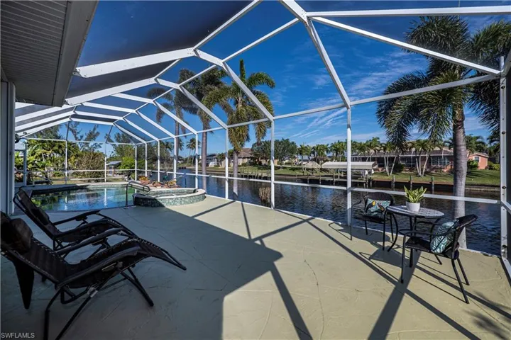 View of pool with a water view, a pool with connected hot tub, glass enclosure, and a patio area