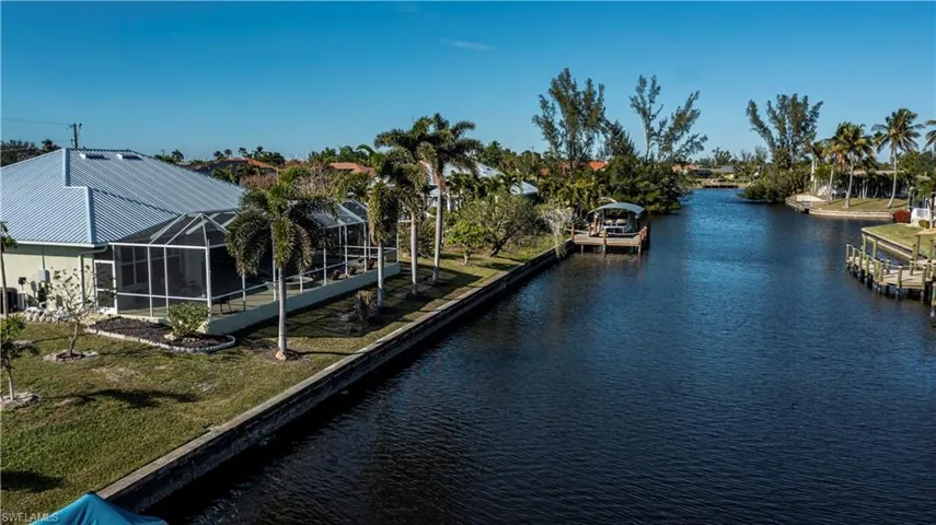 Dock area featuring a water view, a lawn, and a lanai