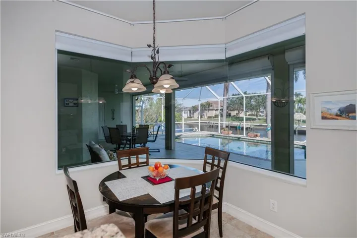 Dining room with a sunroom, a water view, and tile patterned floors