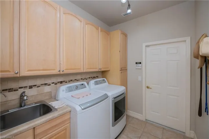 Laundry room featuring washing machine and clothes dryer, light tile patterned flooring, and cabinet space