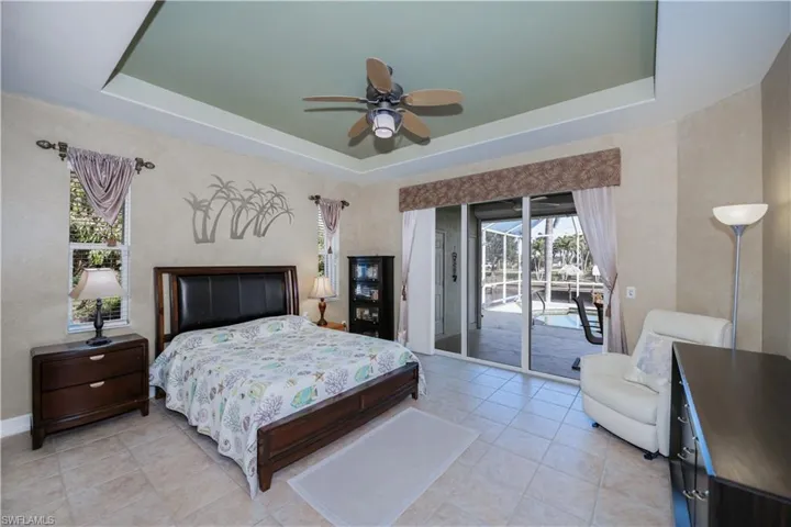 Bedroom with a tray ceiling, access to exterior, and light tile patterned floors
