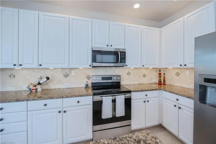 Kitchen featuring appliances with stainless steel finishes, tasteful backsplash, stone countertops, white cabinetry, and recessed lighting