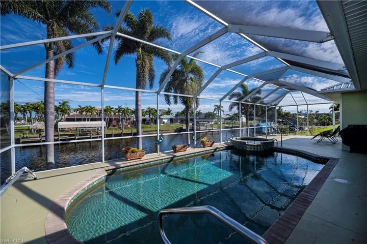 View of swimming pool with a water view, a patio, a pool with connected hot tub, a lanai, and a boat dock