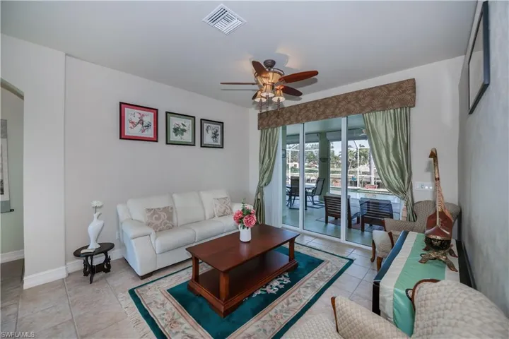 Living room with ceiling fan and light tile patterned flooring