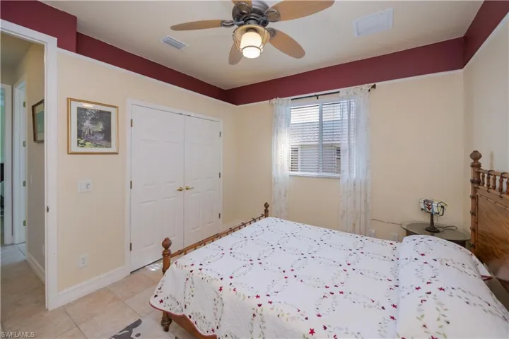 Bedroom featuring a closet, light tile patterned floors, and a ceiling fan