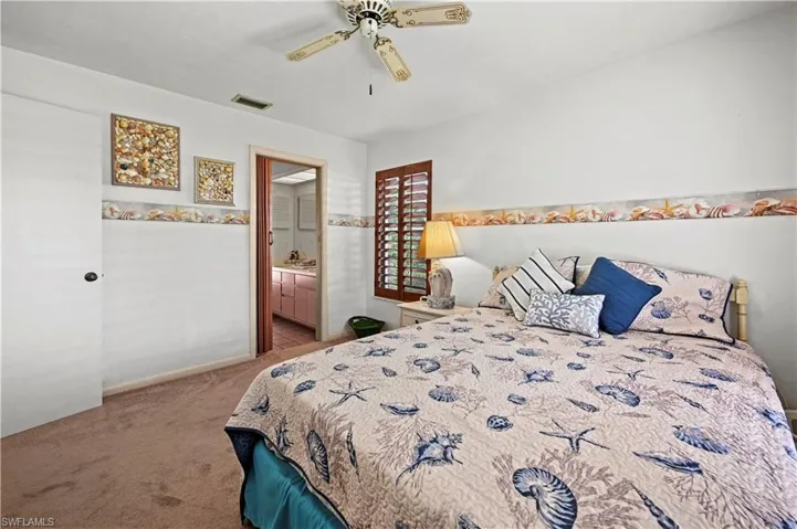 Bedroom featuring connected bathroom, light carpet, and ceiling fan