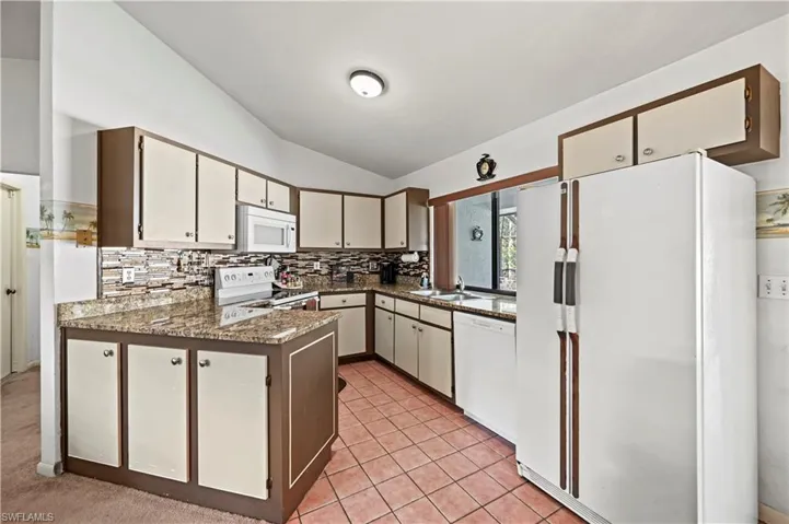 Kitchen featuring lofted ceiling, sink, white cabinets, and white appliances
