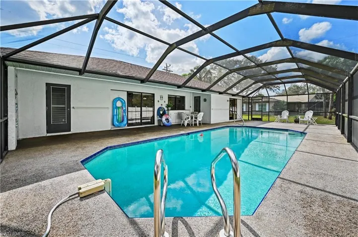 View of pool featuring a patio and glass enclosure