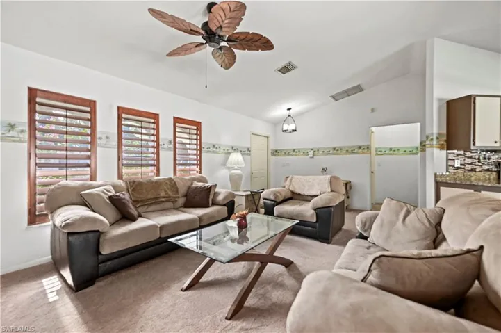 Carpeted living room featuring ceiling fan and lofted ceiling