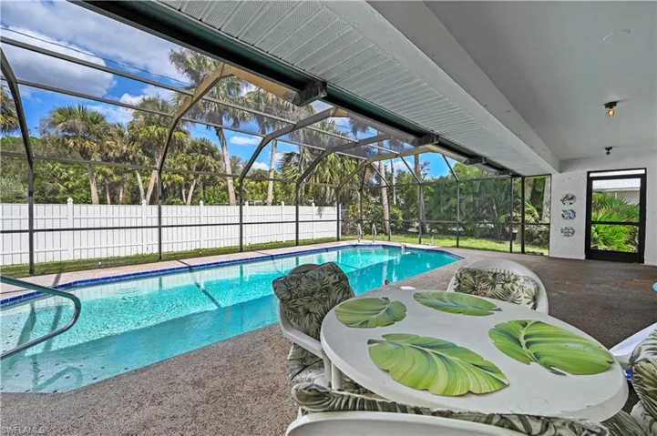 View of pool featuring a patio area and glass enclosure