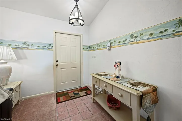 Carpeted foyer entrance with a chandelier