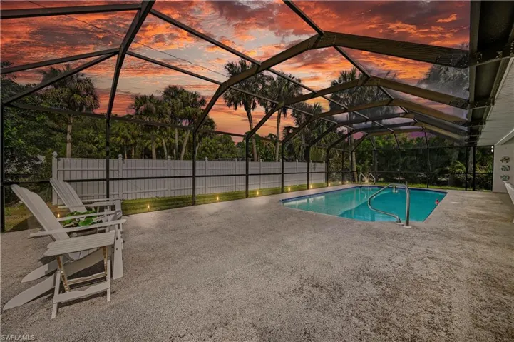 Pool at dusk featuring a lanai and a patio area VIrtual Twilight