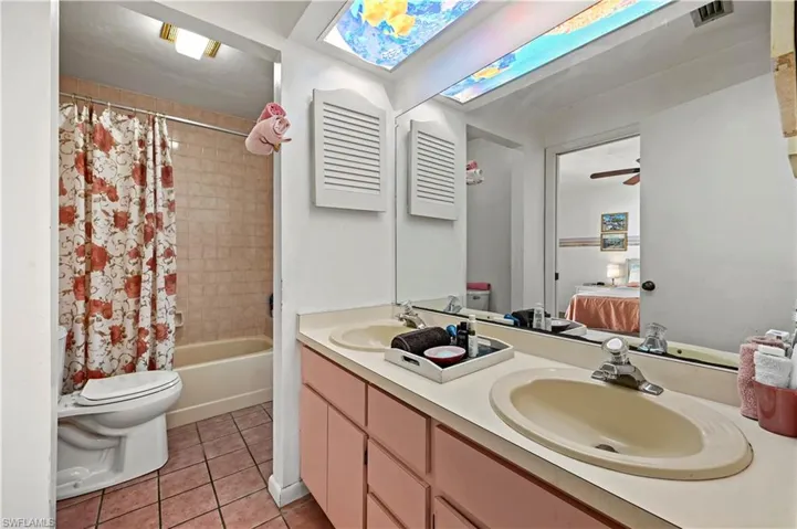 Full bathroom with shower / tub combo with curtain, ceiling fan, tile patterned flooring, vanity, and toilet