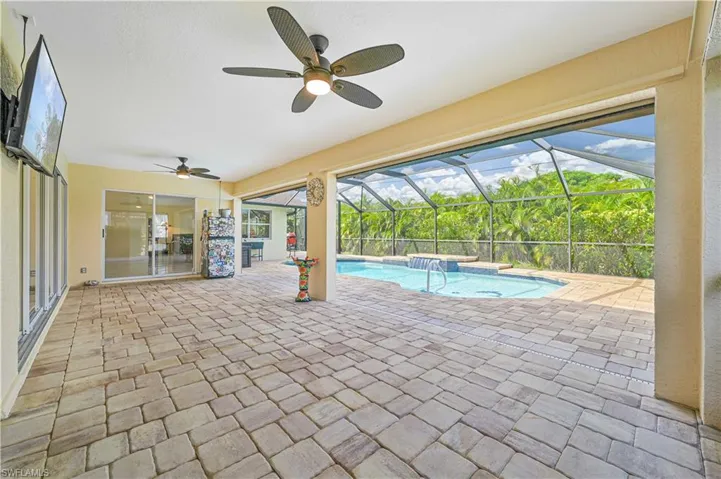 View of swimming pool with a patio, ceiling fan, and a lanai