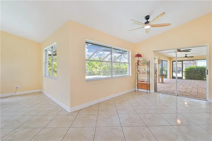 Tiled empty room featuring ceiling fan and vaulted ceiling