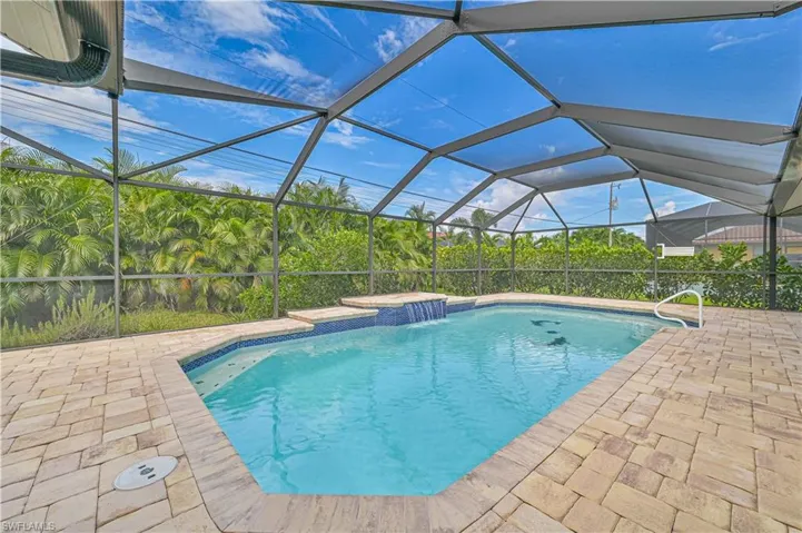View of swimming pool with a jacuzzi, pool water feature, a patio area, and a lanai