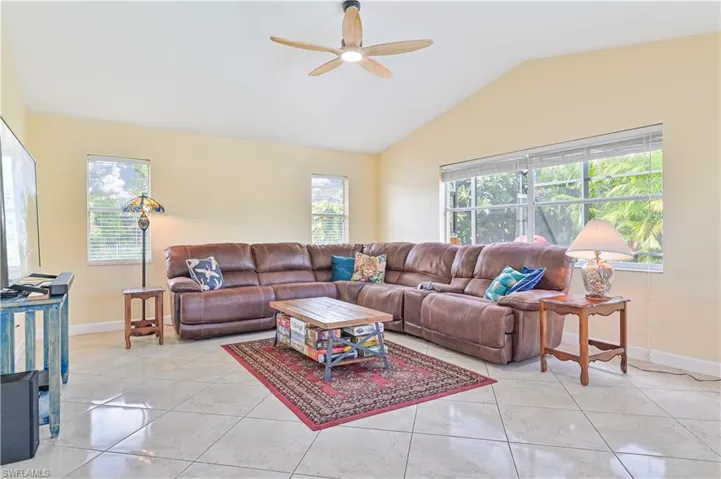 Tiled living room featuring lofted ceiling and ceiling fan