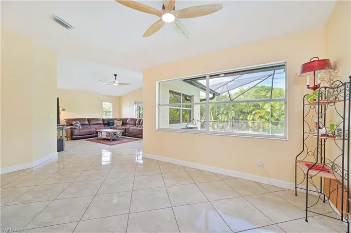 Living room featuring vaulted ceiling, ceiling fan, and light tile patterned floors