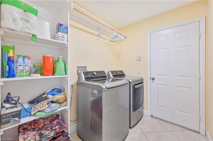 Laundry room with washing machine and clothes dryer and light tile patterned floors