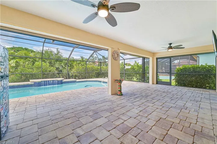 View of pool with a patio, pool water feature, a lanai, and ceiling fan