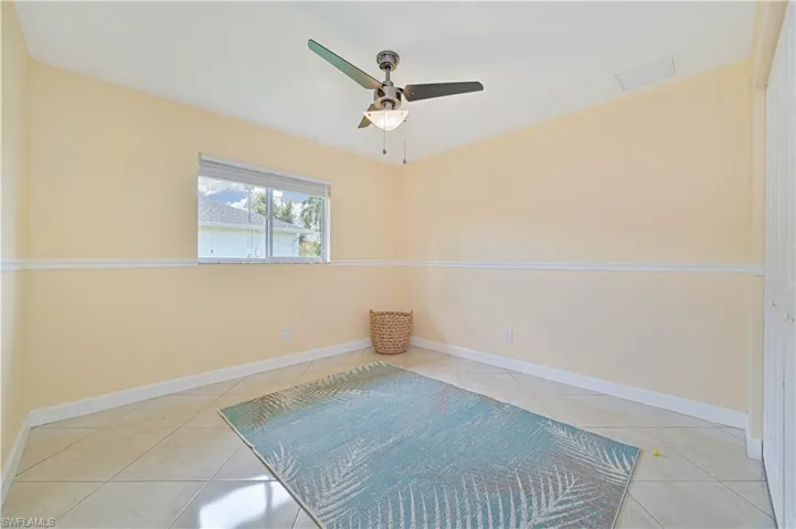 Tiled spare room featuring ceiling fan