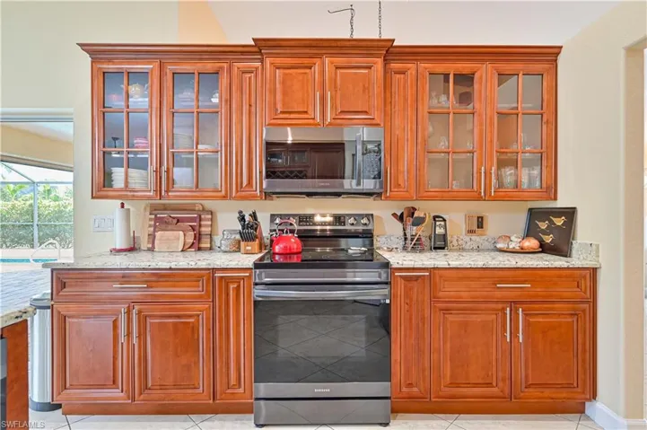 Kitchen with appliances with stainless steel finishes, light stone counters, and light tile patterned floors