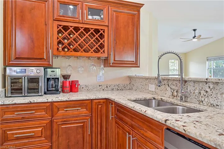 Kitchen with light stone countertops, lofted ceiling, sink, and stainless steel dishwasher