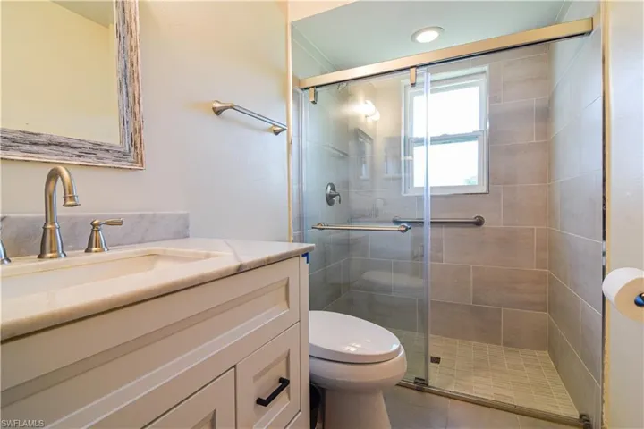 Bathroom with walk in shower, vanity, toilet, and tile floors