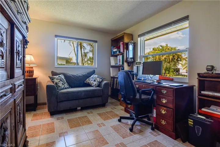 Office with a wealth of natural light, a textured ceiling, and light tile floors