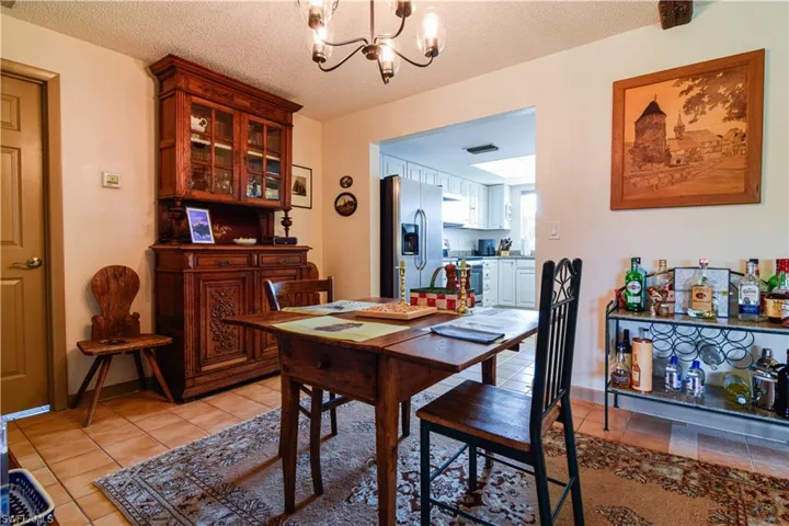 Dining space featuring an inviting chandelier, light tile flooring, and a textured ceiling