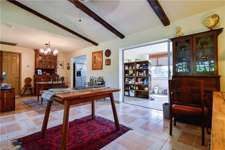 Tiled dining room featuring a chandelier, a textured ceiling, and vaulted ceiling with beams