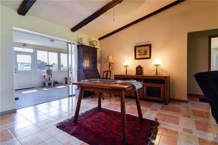 Dining area with lofted ceiling with beams, a textured ceiling, and light tile floors